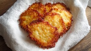 Щойно смажені золотисті деруни лежать на паперовому рушнику для вбирання зайвого жиру.