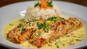 Лосось у вершковому соусі з кропом і спеціями на тарілці.